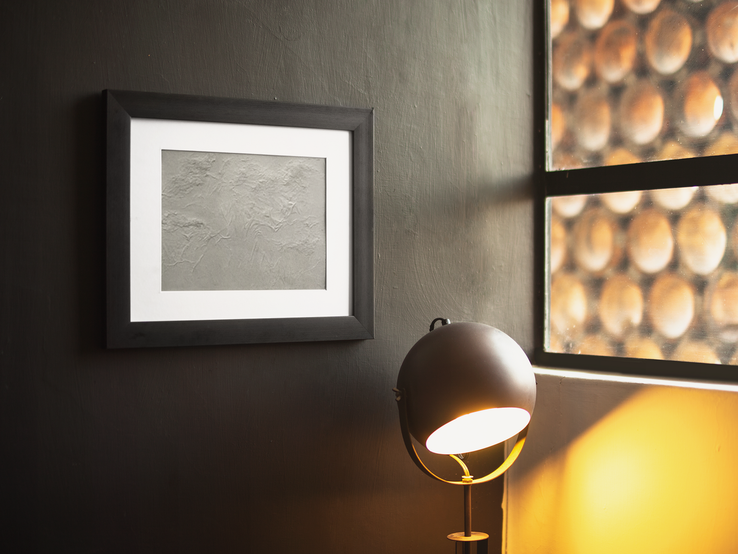 Framed artwork on a wall with a lamp casting light on it